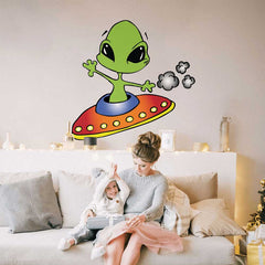 Woman and child sitting on a couch with a 46x48 inch wall decal of an alien on a UFO.
